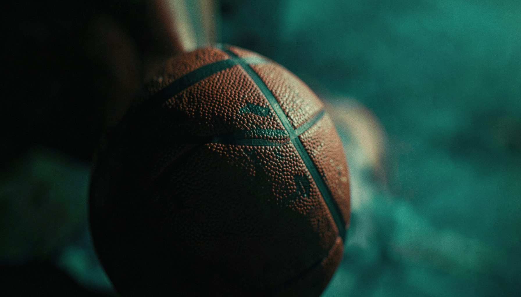 Lacivert ve turuncu tonlarında, bir basketbol potasının yakın çekim silüeti, dramatik aydınlatma