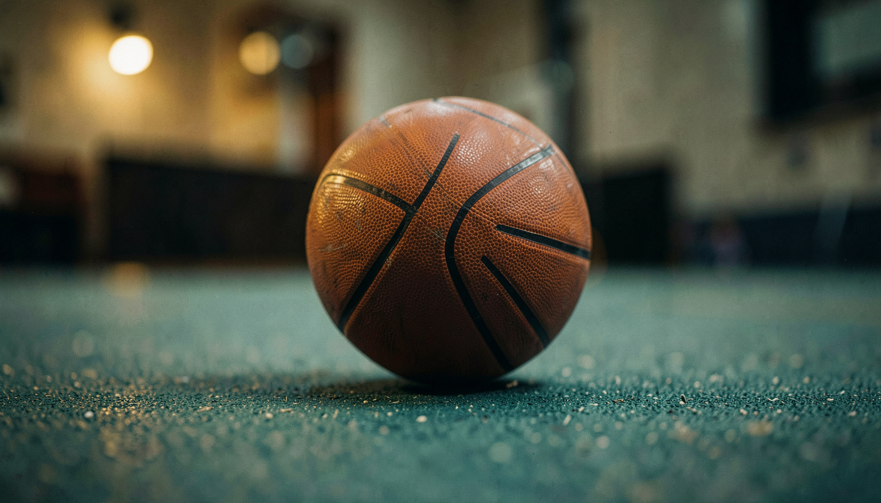 Basketbol topu parke zeminde yakın çekim, turuncu-kahverengi top ve sıcak salon ışıkları
