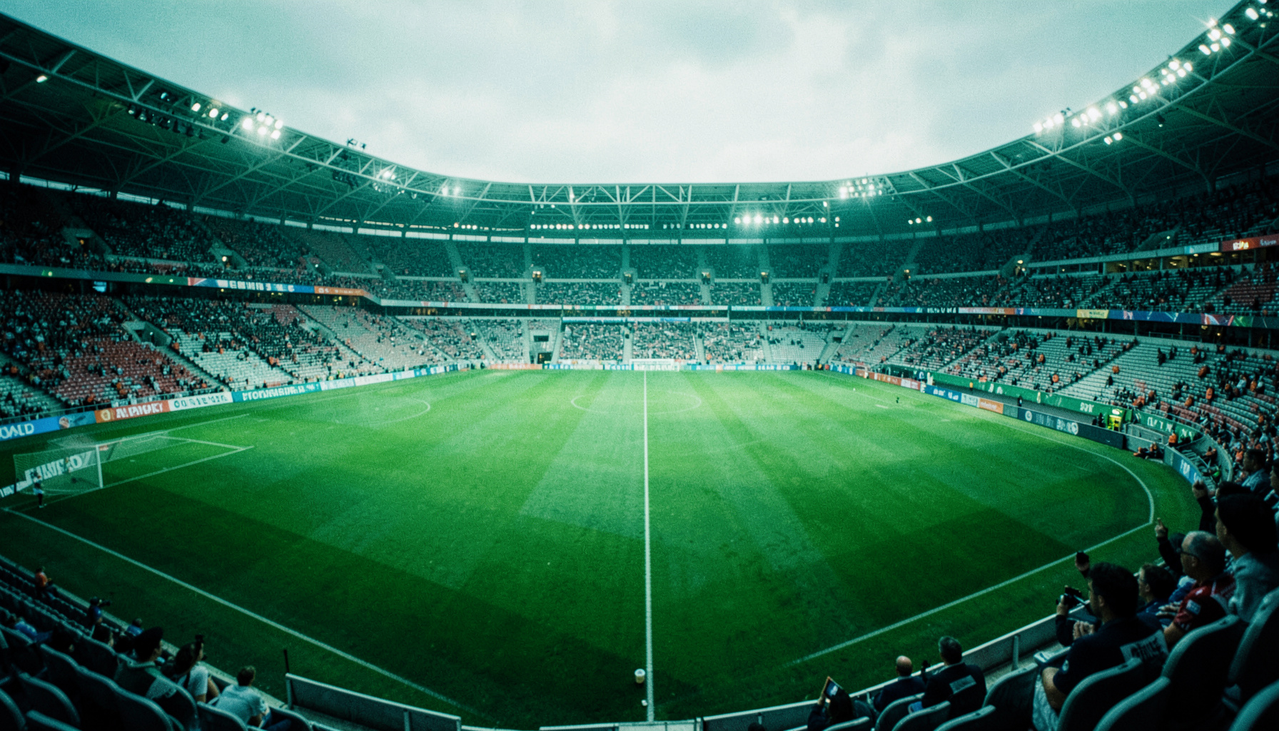 Futbol stadyumu panoramik görünüm, yeşil çim ve dolu tribünler, canlı maç atmosferi